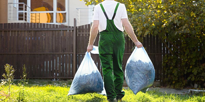 junk removal crew member removing bags of yard waste